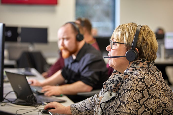 SNG employees working in an office, wearing headsets and talking to customers 