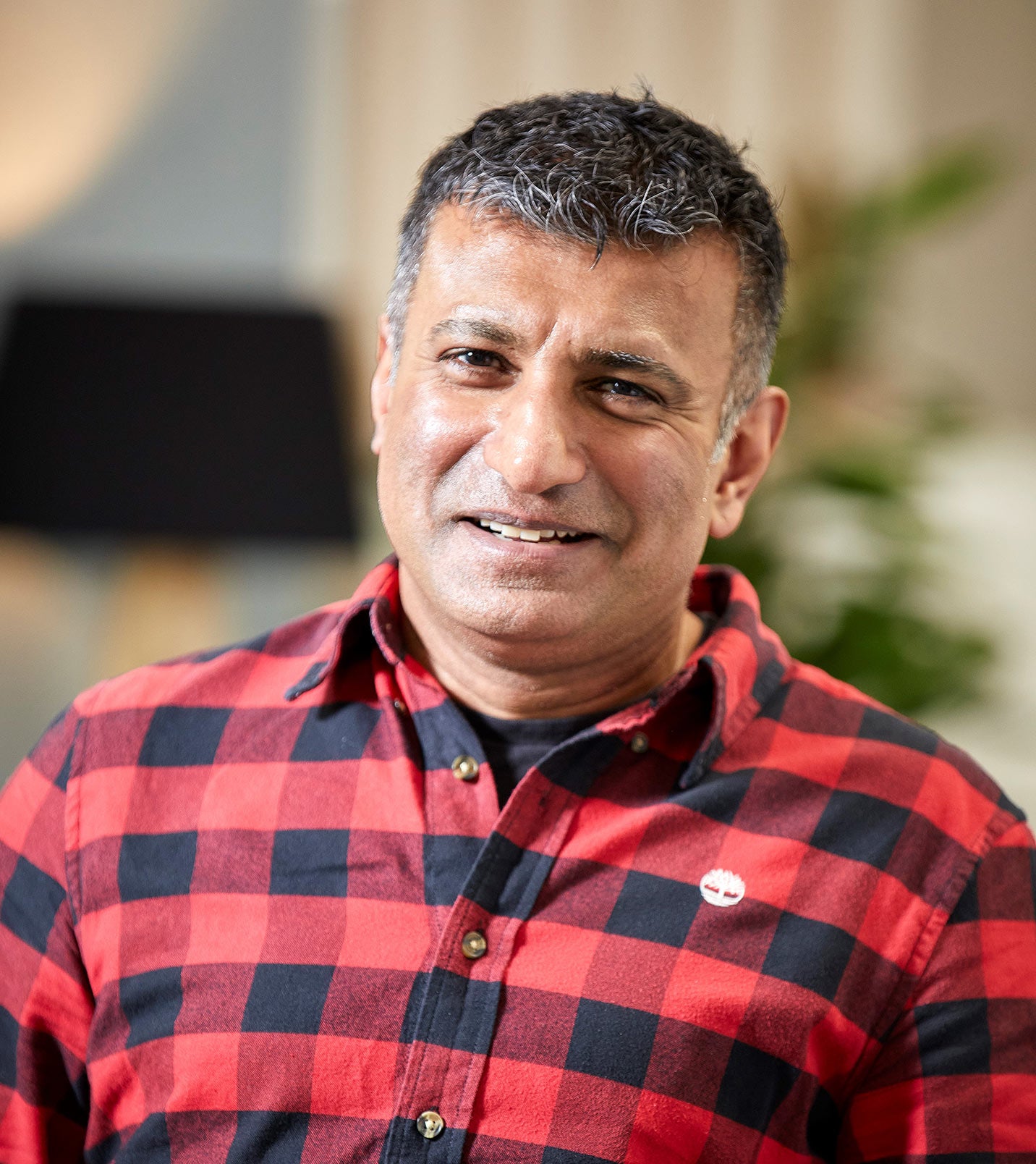 Profile picture of a man wearing a red and black checked shirt. He is smiling at the camera.