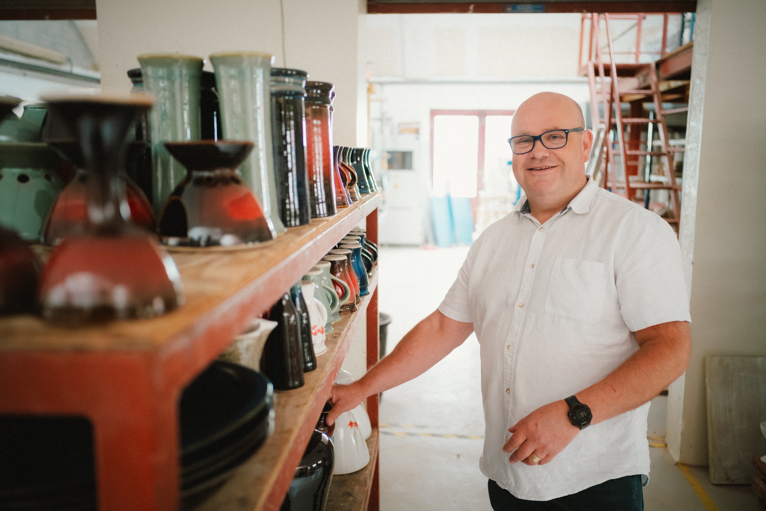 A man standing next to a shelf with vases