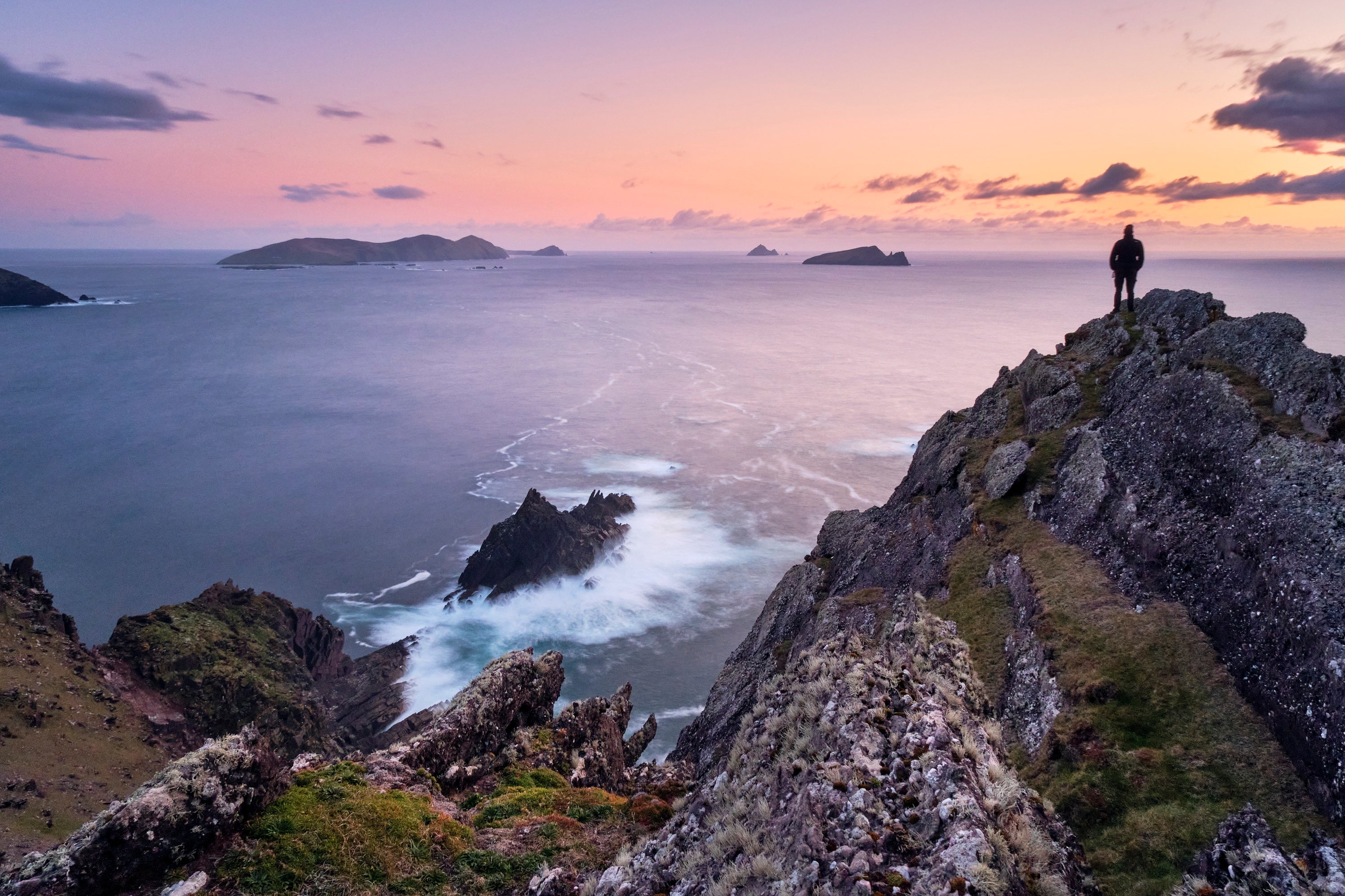 A person standing on a cliff overlooking a body of water