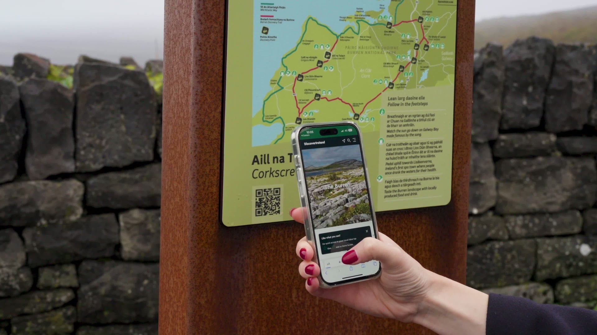 Person holding a smartphone at an outdoor trail sign