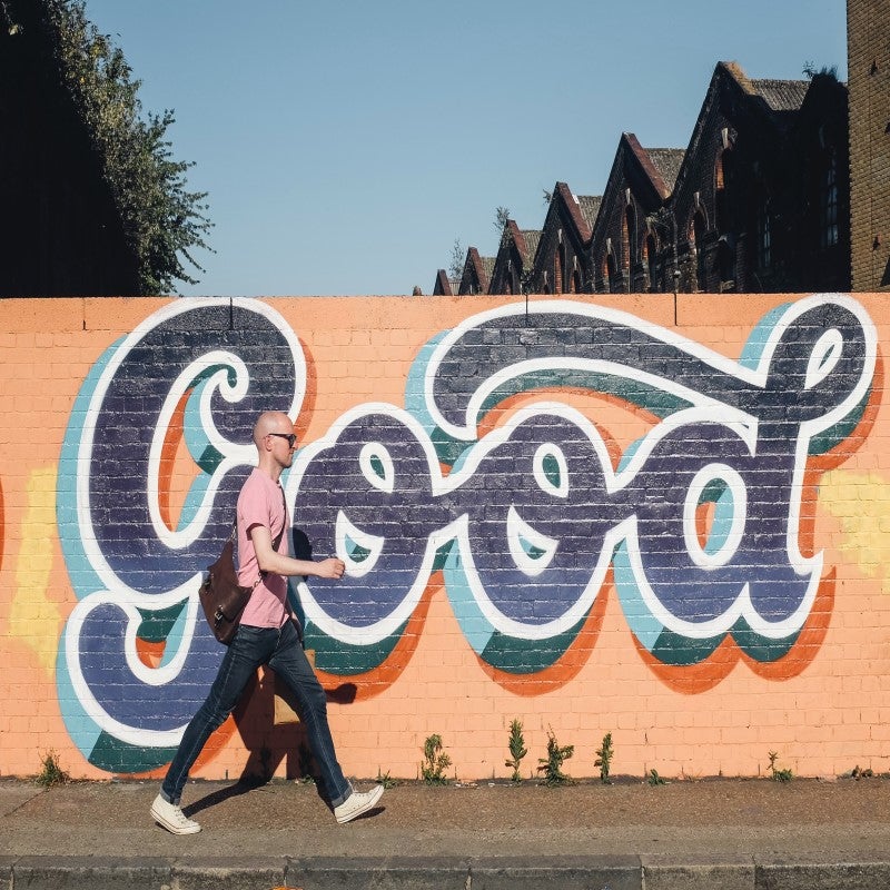 man walking in front of wall mural
