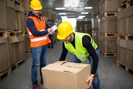 Muž v žltej prilbe drží škatuľu