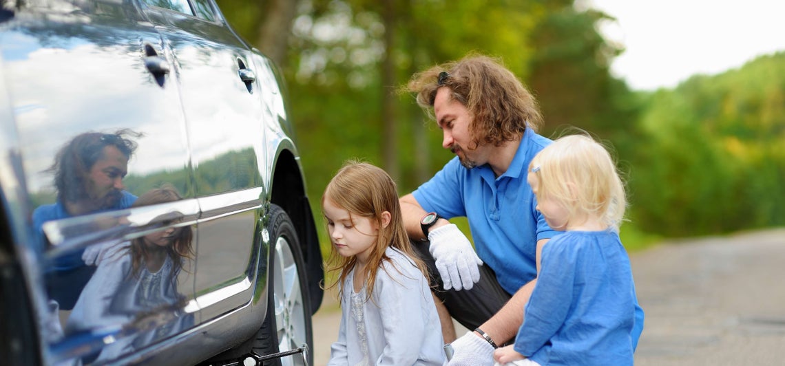 Muž a dve dievčatá sa pozerajú na pneumatiku
