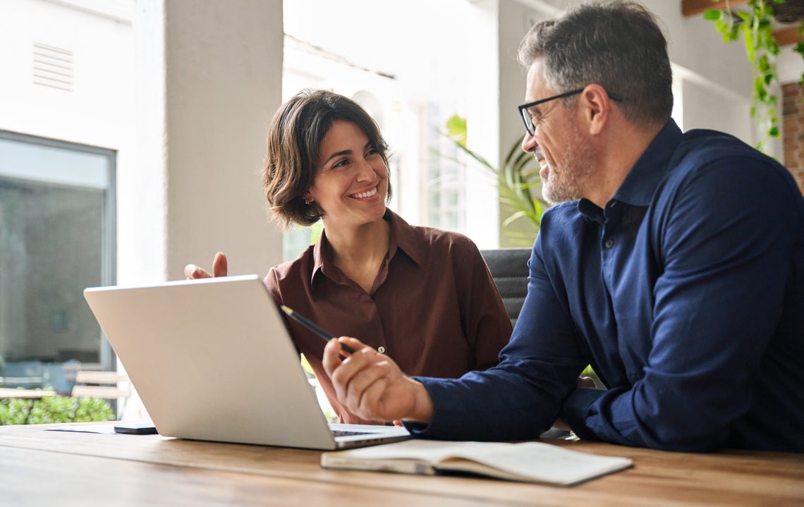 Muž a žena sedia za stolom a pozerajú na notebook