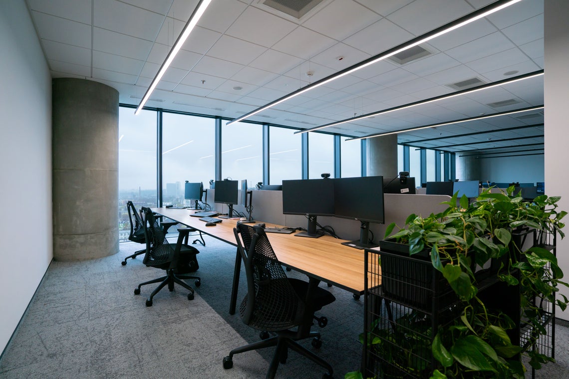 Pokój z dużym biurkiem i ekranami komputerowymi