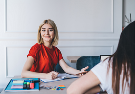 Žena sediaca za stolom s knihou a perom