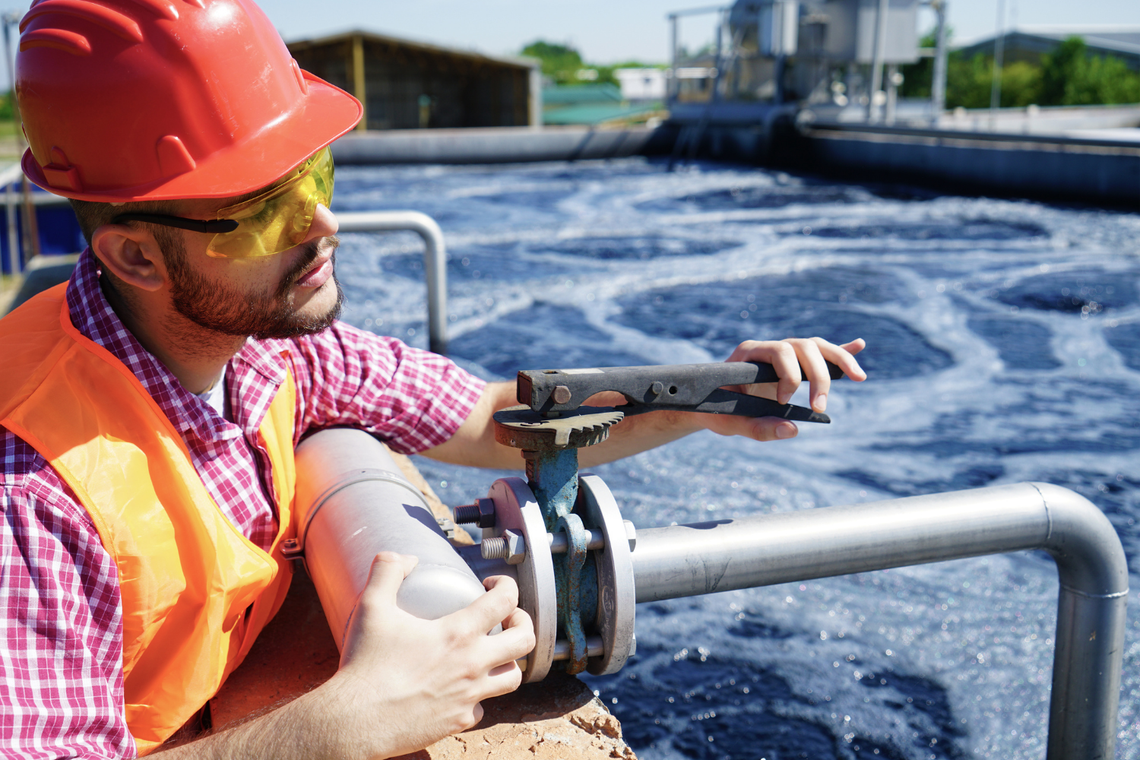 Mężczyzna w kasku ochronnym i okularach ochronnych trzymający klucz