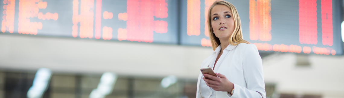 Žena drží telefón na letisku