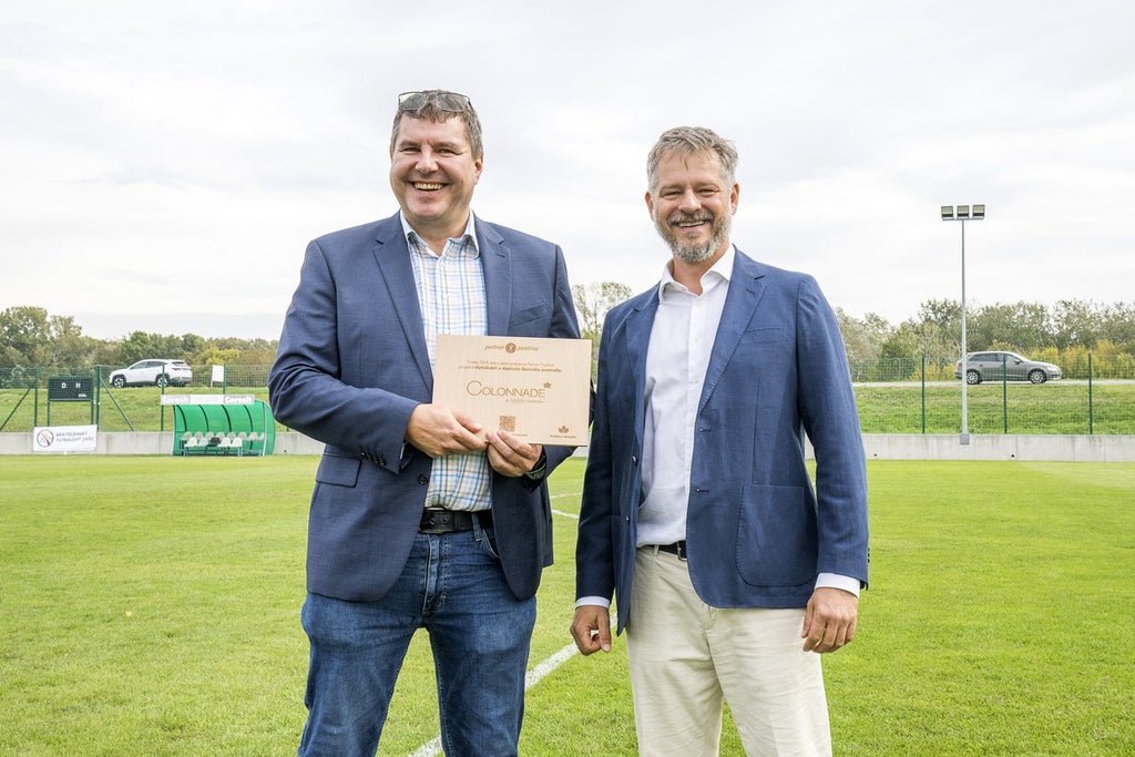 Dvaja muži stojaci na poli a držiaci nápis