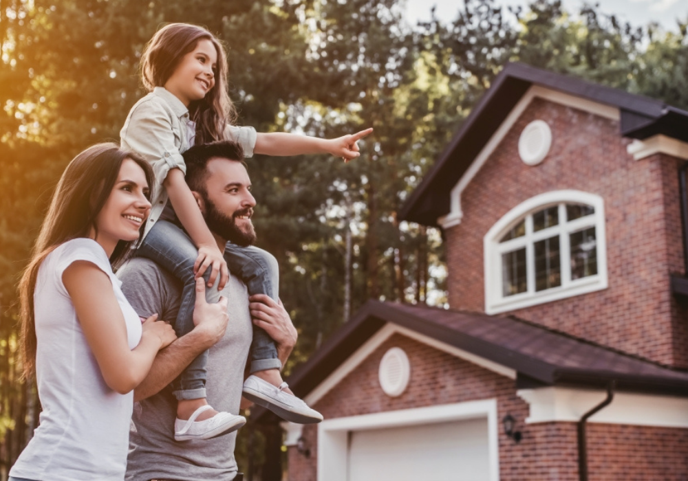 Muž nesie na pleciach dieťa pred domom