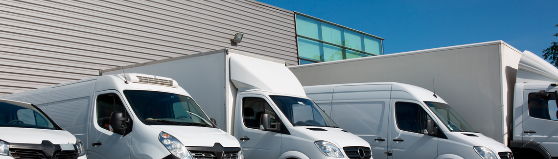 Bílá nákladní auta zaparkovaná před budovou