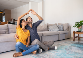 Muž a žena sedia na zemi s rukami nad hlavou