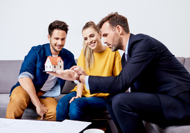 Skupina ľudí sedí na pohovke a pozerá sa na malý domček