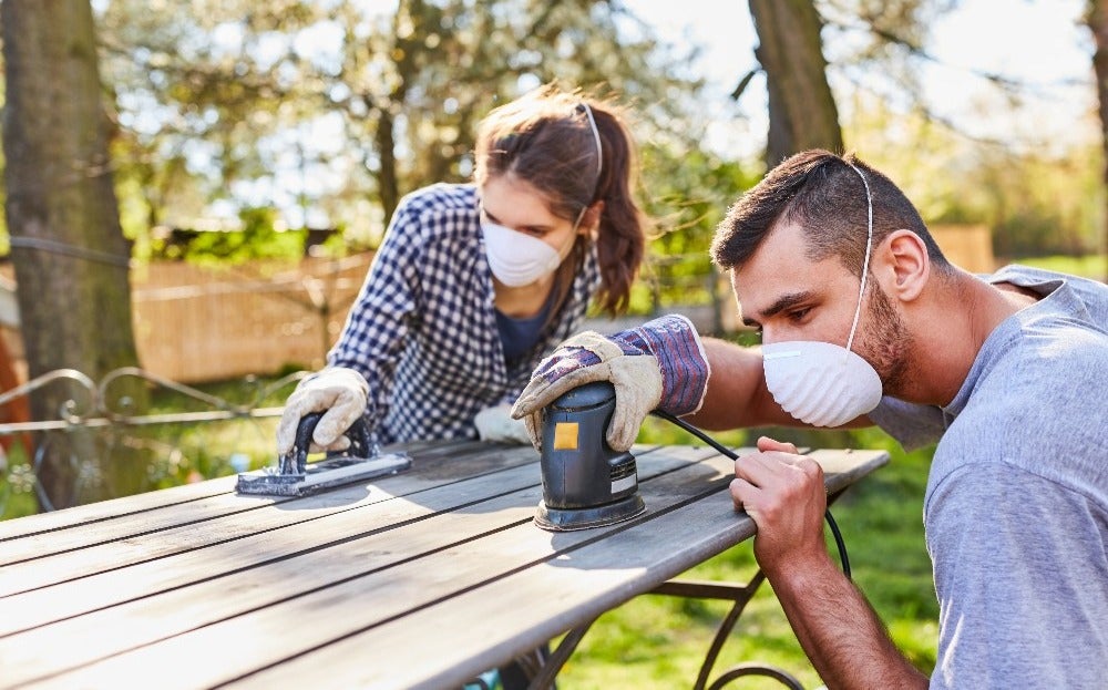 Muž a žena s maskami na tvári pracujú na stole