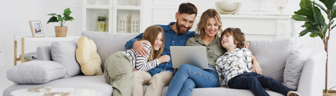 Szczęśliwa rodzina siedząca razem w salonie przy komputerze 
