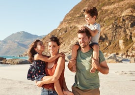 Mężczyzna i kobieta z dwójką dzieci na ramionach na plaży