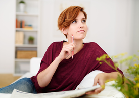 Žena drží pero a pozerá nahor