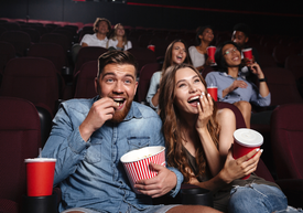 Mężczyzna i kobieta jedzący popcorn w kinie