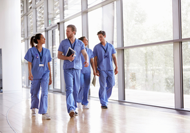 Skupina ľudí v modrých šatách kráčajúcich po chodbe