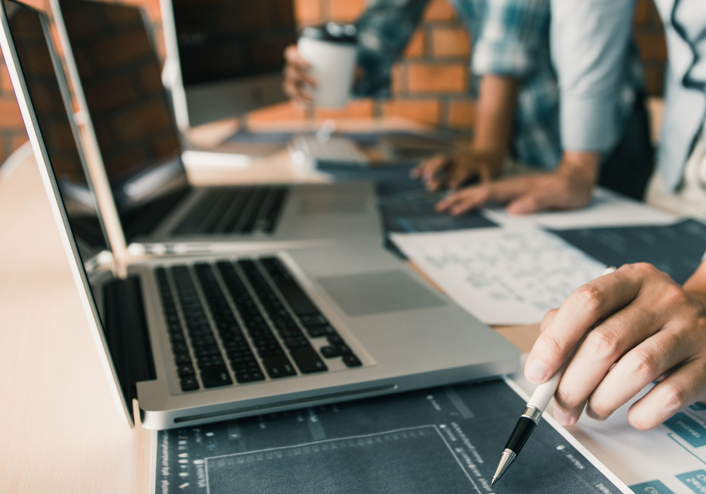 Osoba držiaca pero a pozerajúca sa na notebook