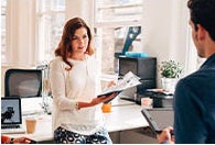 Žena drží knihu a pozerá na muža v kancelárii