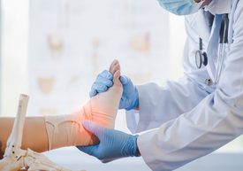 Lékař obvazuje pacientovi kotník