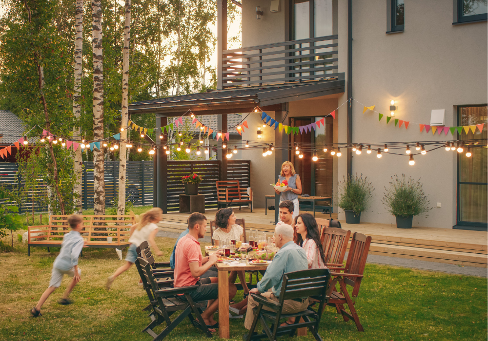 Skupina ľudí sediaca okolo stola pred domom