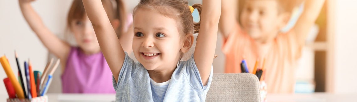 happy kids in school raising hands 