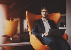 Muž sediaci na stoličke s notebookom