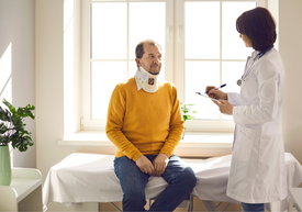 Lékař kontrolující muže s krční ortézou