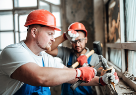 Skupina mužov v tvrdých klobúkoch držiacich kladivá
