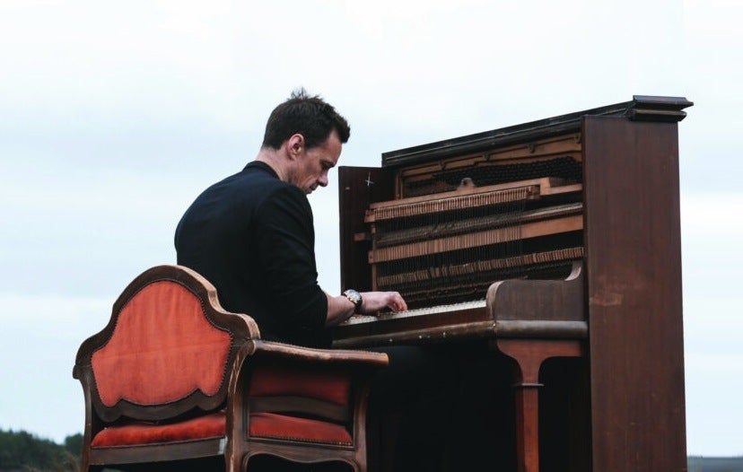 Niall Breslin playing an upright piano outdoors