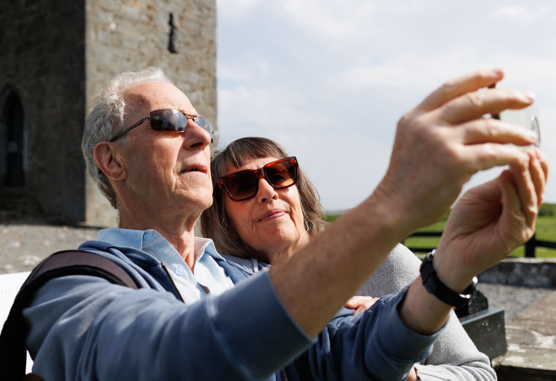 Two people wearing sunglasses taking a picture in front of a castle
