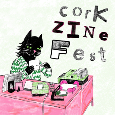 A cat at a desk, making a zine.