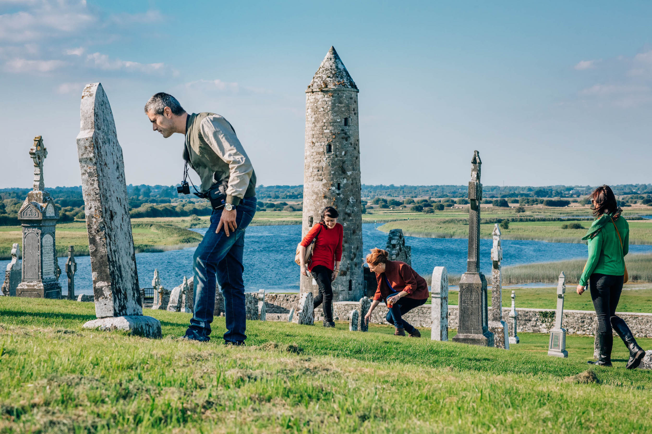 Four people exploring the Clonmacnoise monastic site in County Westmeath.