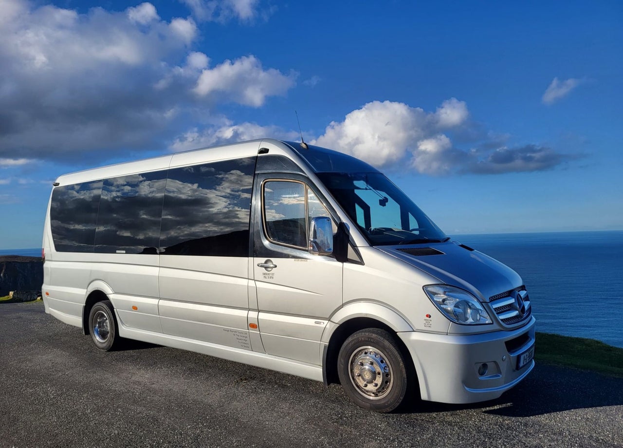 Mercedes tour bus with sea and blue sky in the background