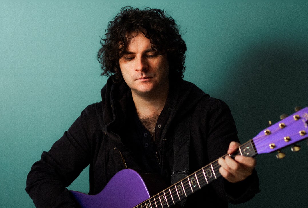 Paddy Casey - a man looking down at a guitar he is playing