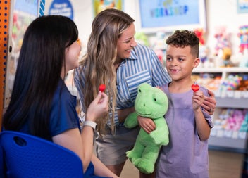 Child and adults with a green bear and red heart