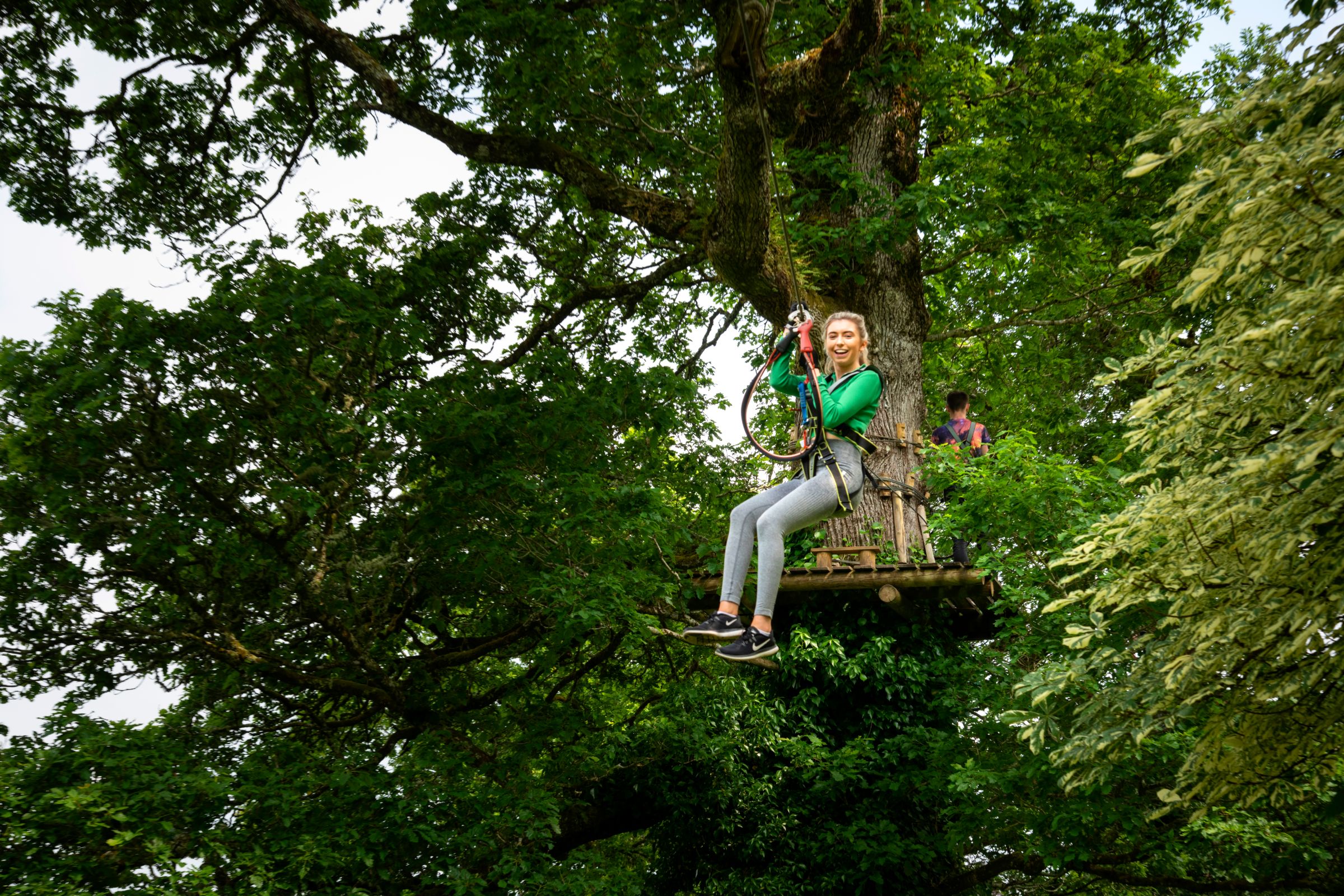 Girl in a green jumping sliding down a zipline in Roscommon