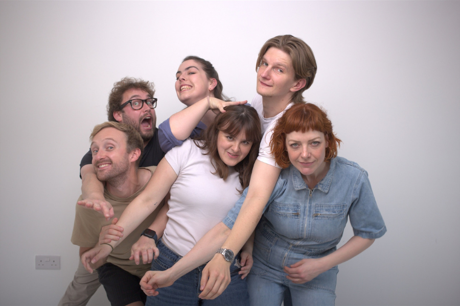 A group of 6 people standing, intertwined with each other.
