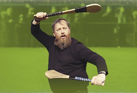 Cornelius Patrick O'Sullivan, a startled looking man holding small wooden bats one above his head, the other out in front of him.