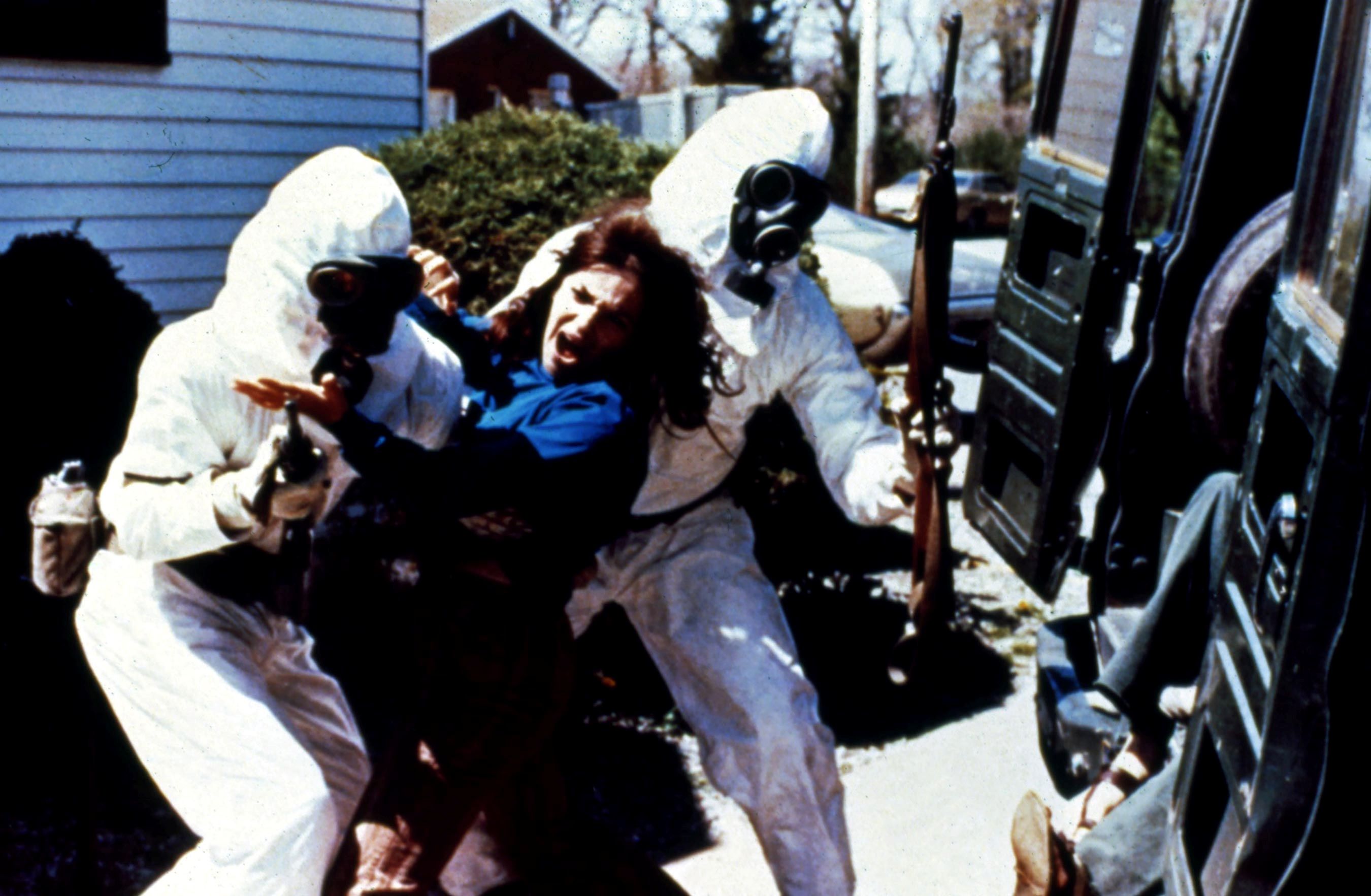 Armed men in hazmat suits are forcing a woman into a vehicle.