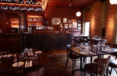 The dining area of a traditional pub with dark wood colours and tables set for dinner