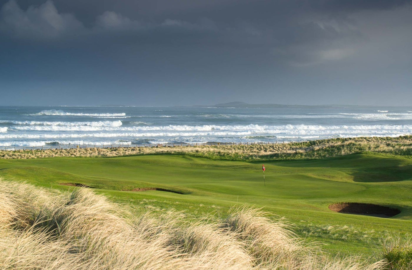 A golf course with a view of the sea as waves roll in