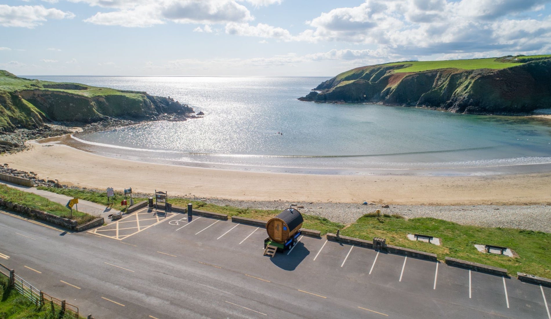An aerial view of a mobile wooden sauna overlooking a beach