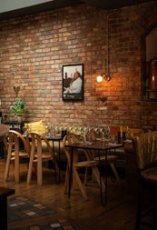 A dining area with tables and chairs with the backdrop of a red bricked wall
