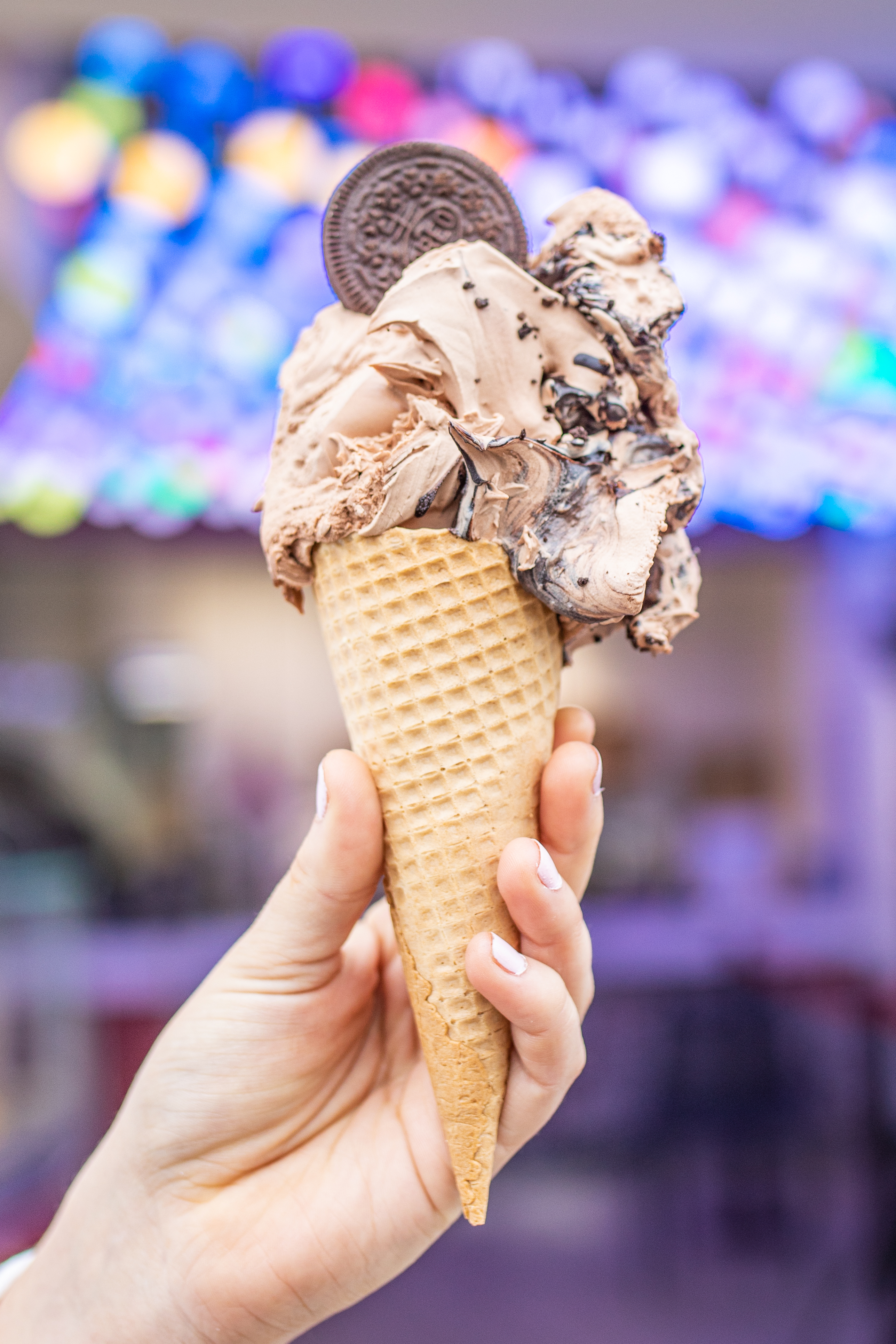 A Gino Gelato cone with topped with a cookie and chocolate sauce 