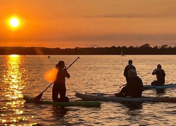 A group of people sitting on the paddle boards out on the water