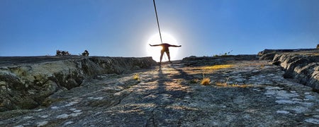 A view taken from the ground looking up at a person abseiling down a rock face